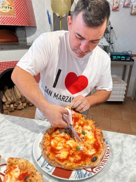 Pizzaiolo Using Pizza Shears To Cut The Pizza